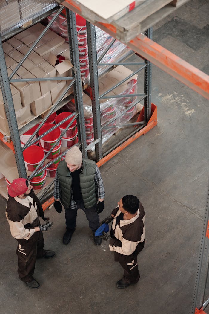 why-choose-us High-angle view of a team discussing logistics in an industrial warehouse setting.